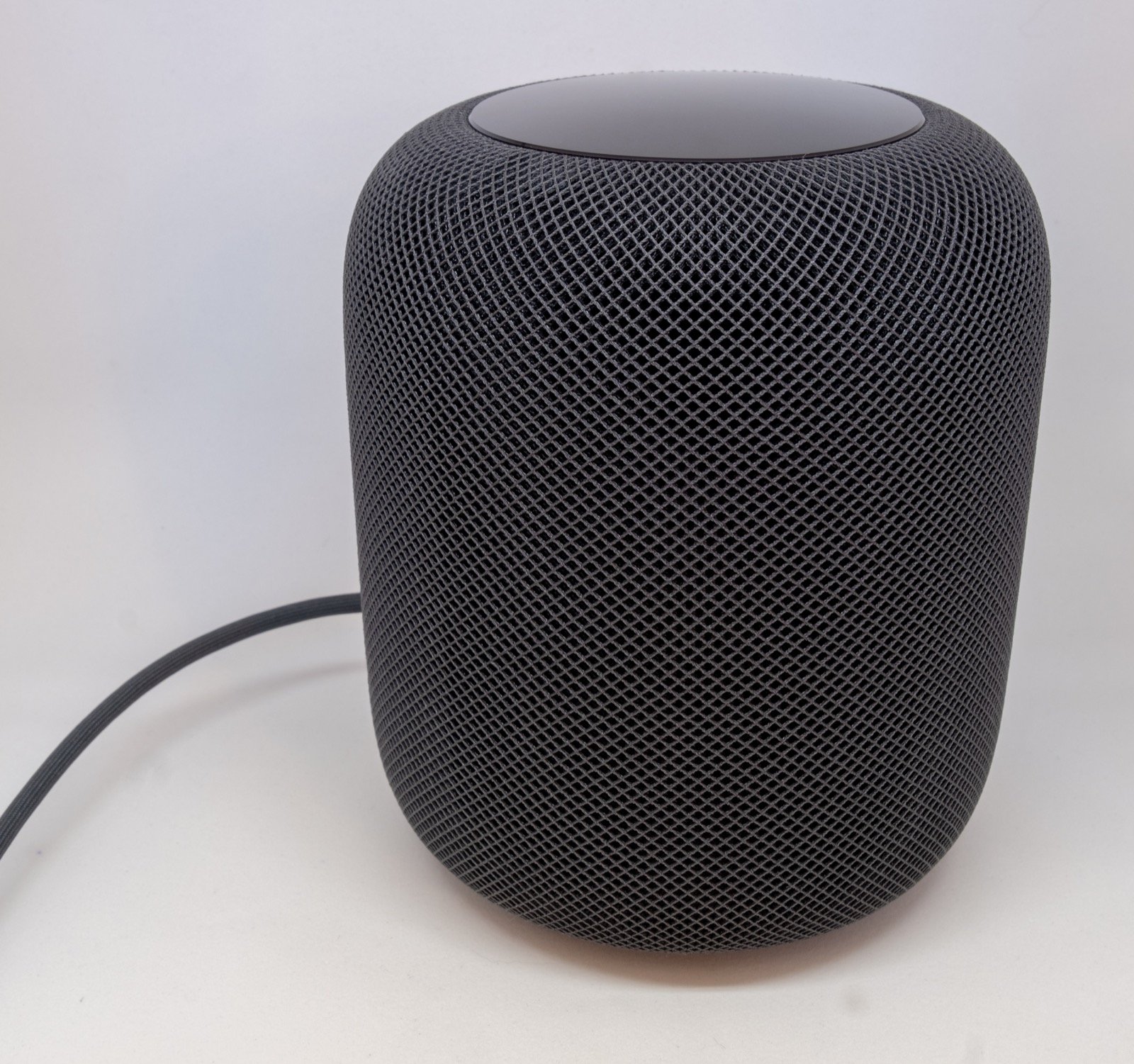 Un HomePod noir photographié sur fond clair, sans texte incrusté.