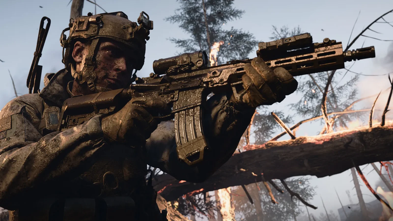 Un soldat couvert de boue, casque et lunette de visée, épaule son fusil au milieu d’arbres calcinés et d’une forêt en flammes, dans Call of Duty: Modern Warfare 4.