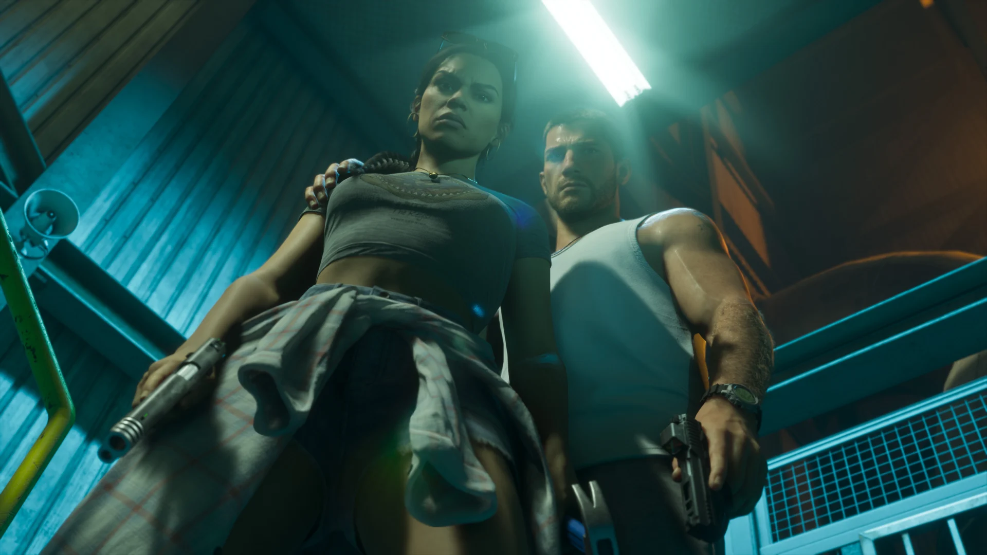 Capture officielle de GTA VI en contre-plongée : Lucia, pistolet à la main, et Jason, la main sur son épaule, dans un escalier métallique éclairé au néon bleu.