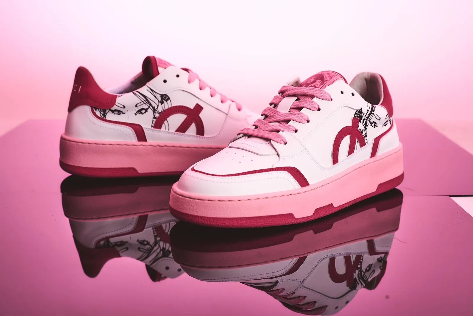 Deux sneakers roses et blanches de la collection Nicki Minaj pour LØCI, sur un fond rose sans texte incrusté.