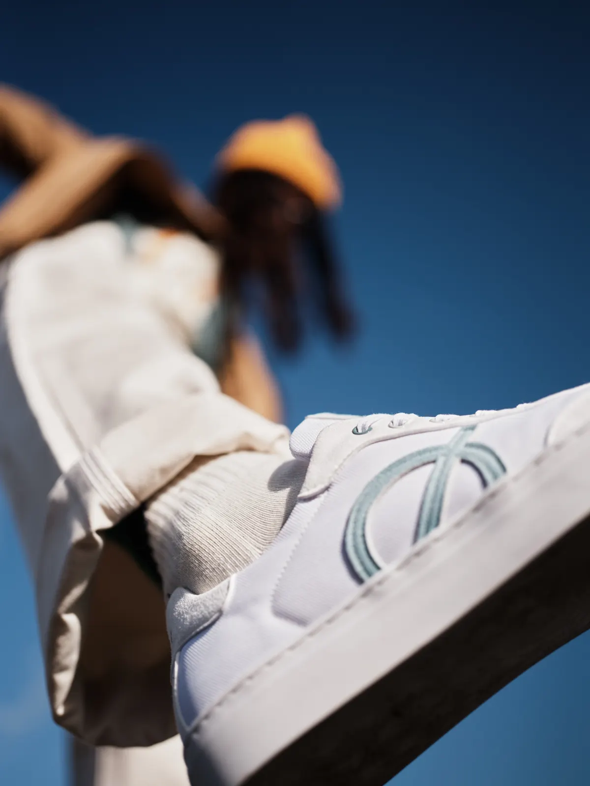 Gros plan d’une sneaker blanche LØCI portée lors d’une campagne de la marque sur fond bleu.