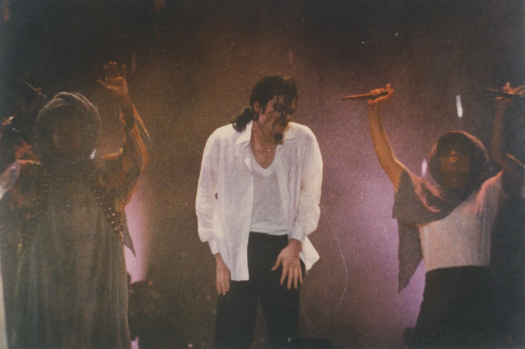 Michael Jackson en chemise blanche sur scène entre deux danseuses, pendant le Dangerous World Tour à Monza en 1992.