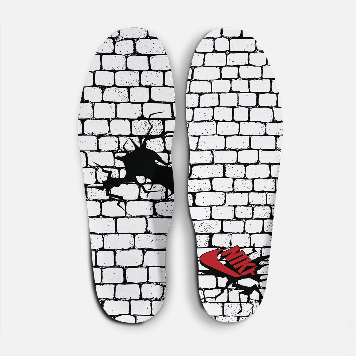 Les deux semelles intérieures de l’Air Force 1 « Philly », imprimées d’un mur de briques fissuré traversé par un Swoosh rouge.