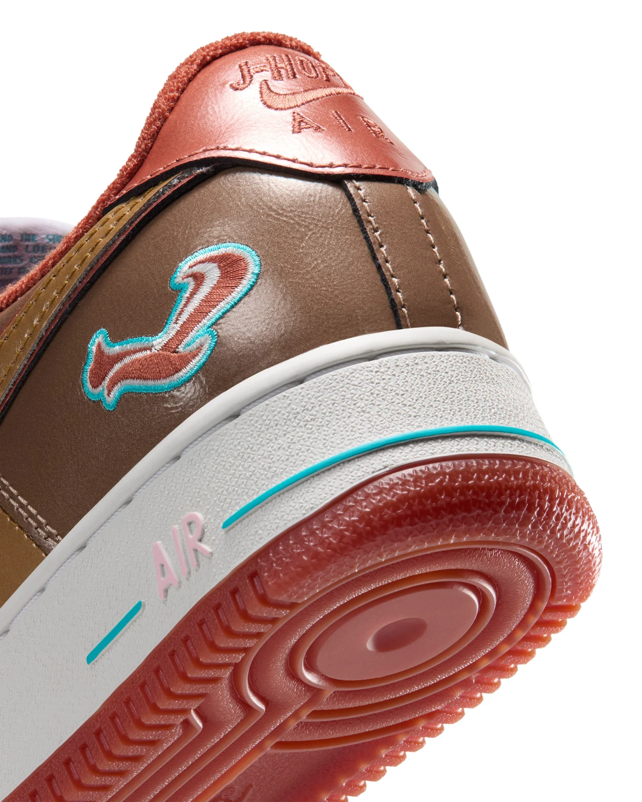 Gros plan sur le talon de la Nike Air Force 1 '01 Nigo × j-hope : écureuil brodé rouge et bleu, talon marqué « j-hope Air », semelle rouge brique.
