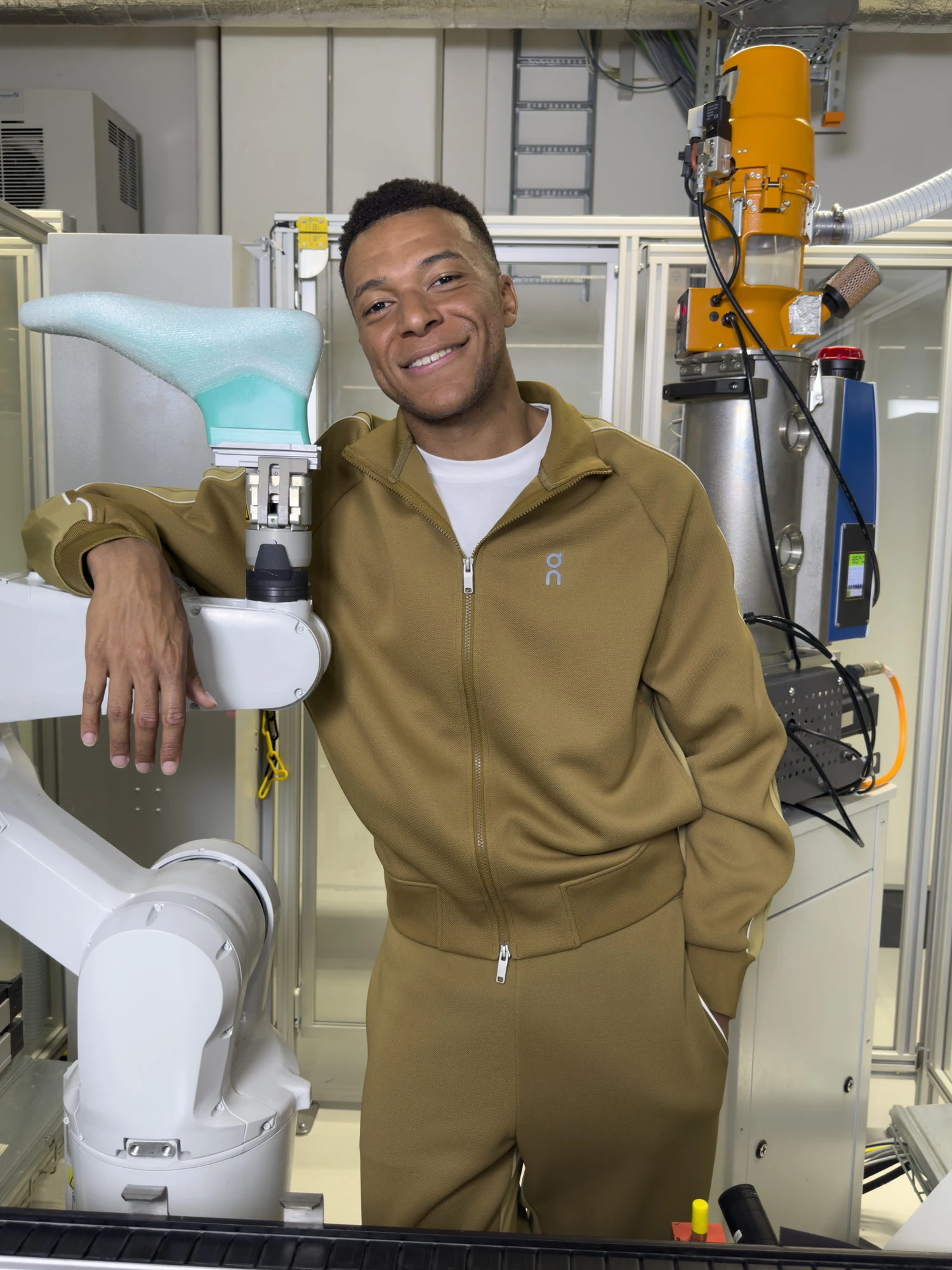 Kylian Mbappé en tenue On, auprès du robot LightSpray aux On Labs à Zurich.