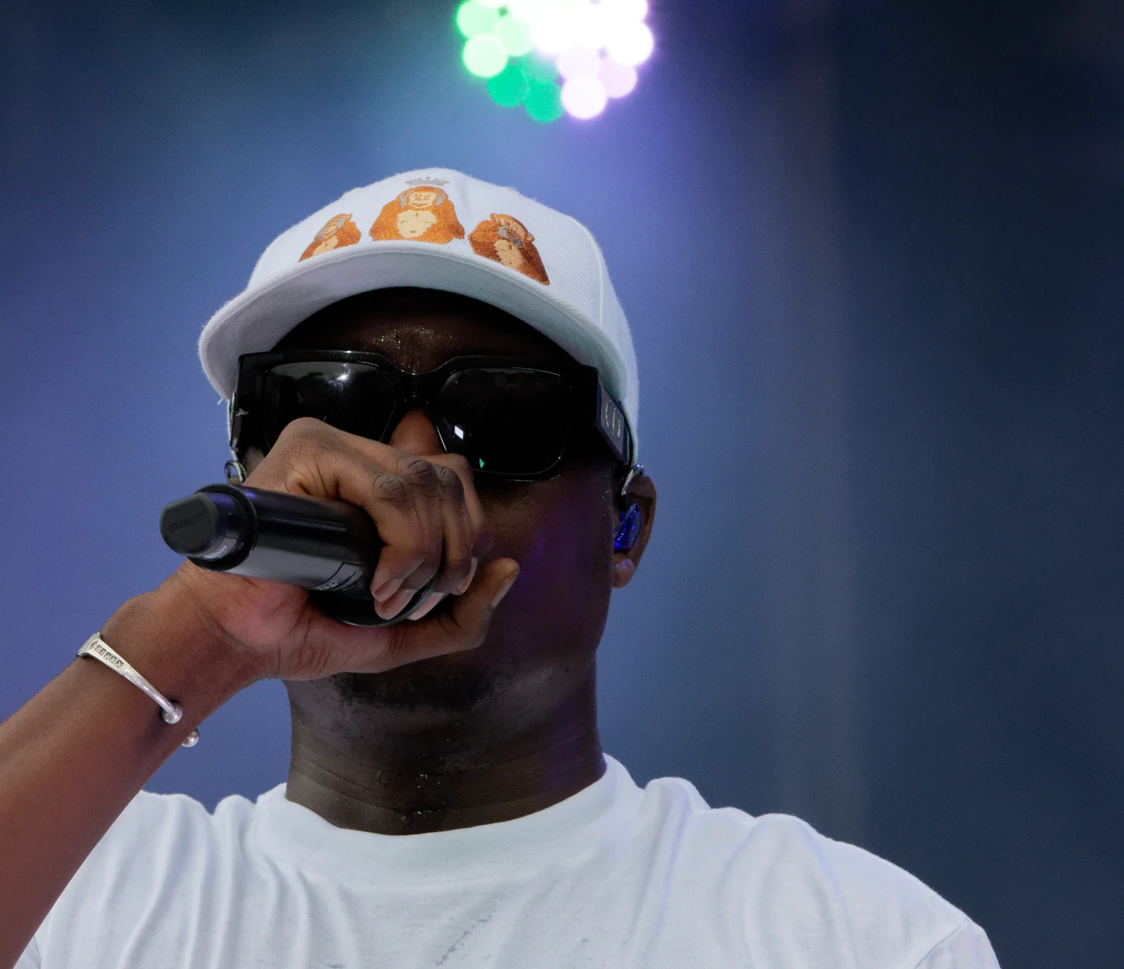 Ninho en casquette blanche et lunettes noires, le micro contre la bouche.