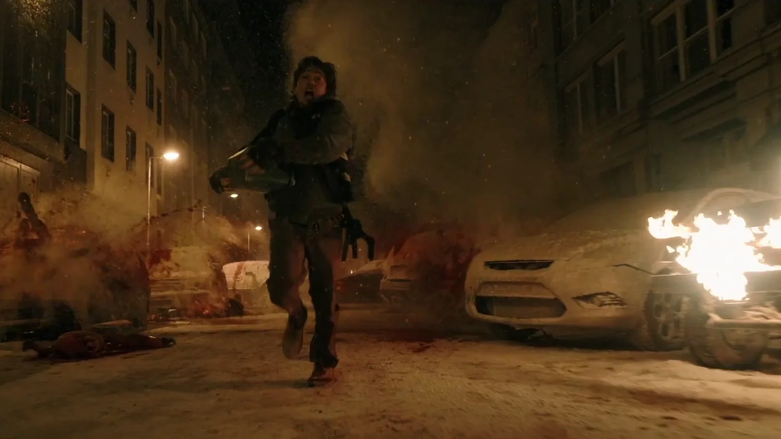 Bryan, le coursier joué par Austin Abrams, court dans une rue enneigée de Raccoon City, entre des voitures en feu et des traces de sang.