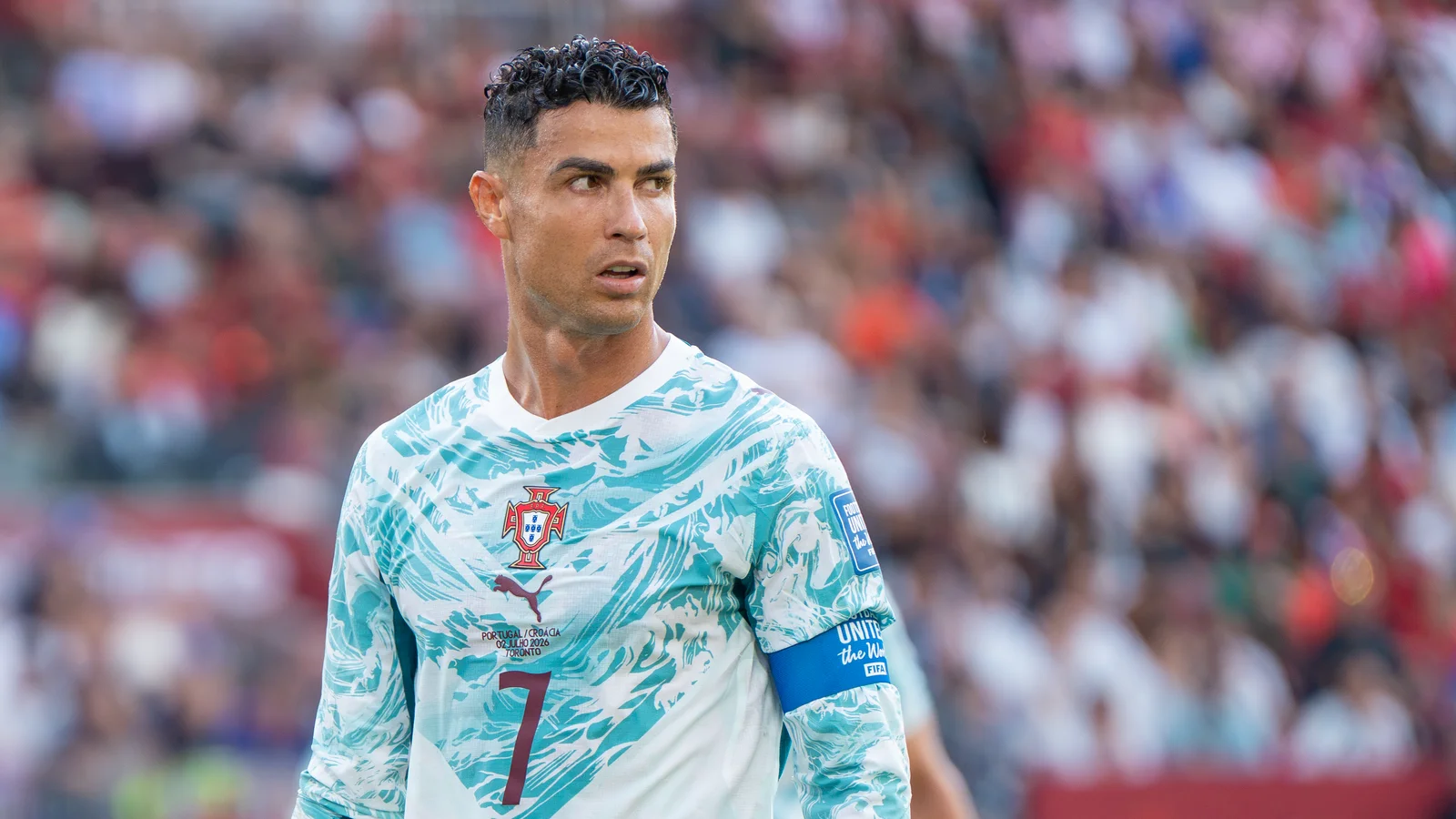 Cristiano Ronaldo, maillot blanc et turquoise du Portugal numéro 7 et brassard de capitaine, regarde sur sa gauche pendant Croatie-Portugal à la Coupe du monde 2026, devant une tribune floue.