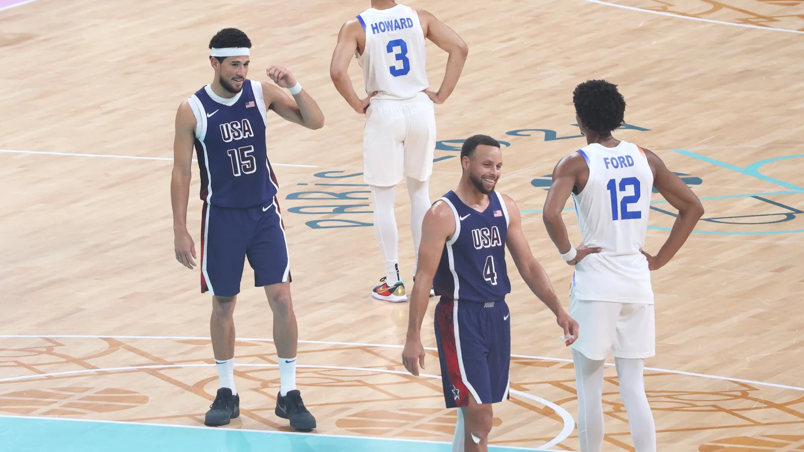 Stephen Curry, souriant sous le maillot de l’équipe des États-Unis, sur le parquet des Jeux olympiques de Paris 2024, avec Devin Booker.