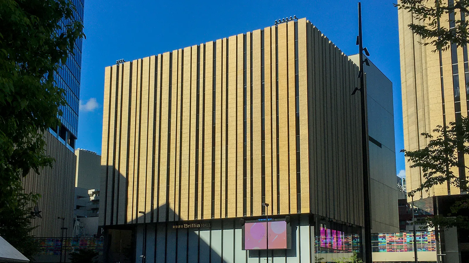 La façade dorée du Tokyo Tatemono Brillia Hall, à Ikebukuro, sous un ciel bleu.
