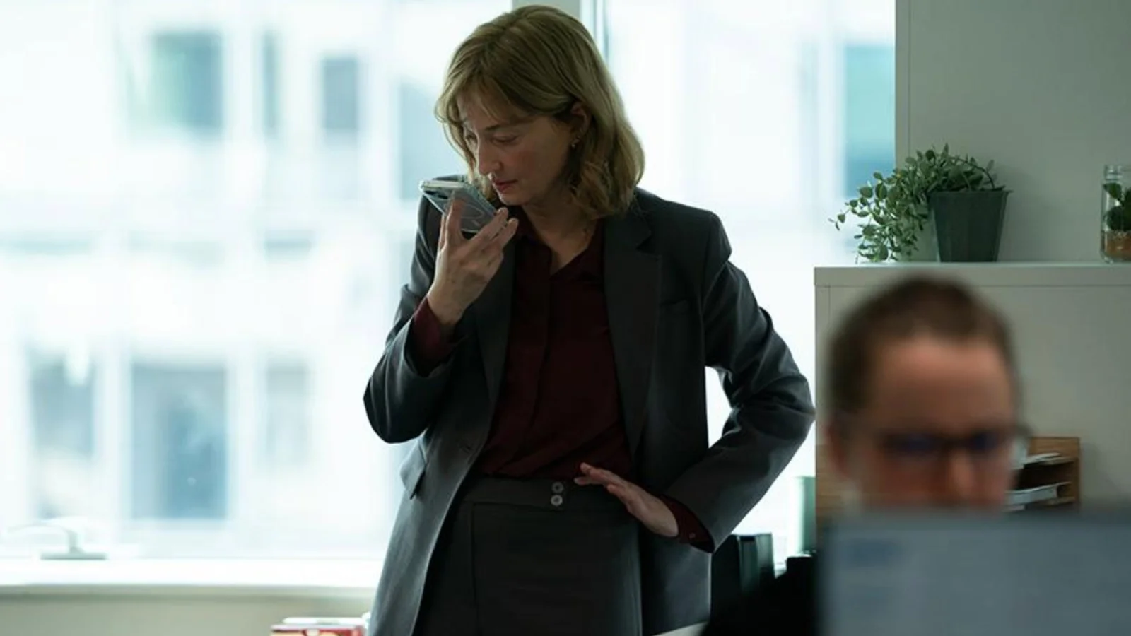 Une scène d’Un bon petit soldat, de Stéphane Brizé : Alba Rohrwacher, en blazer gris, parle dans son téléphone dans un bureau lumineux, un collègue flou au premier plan.