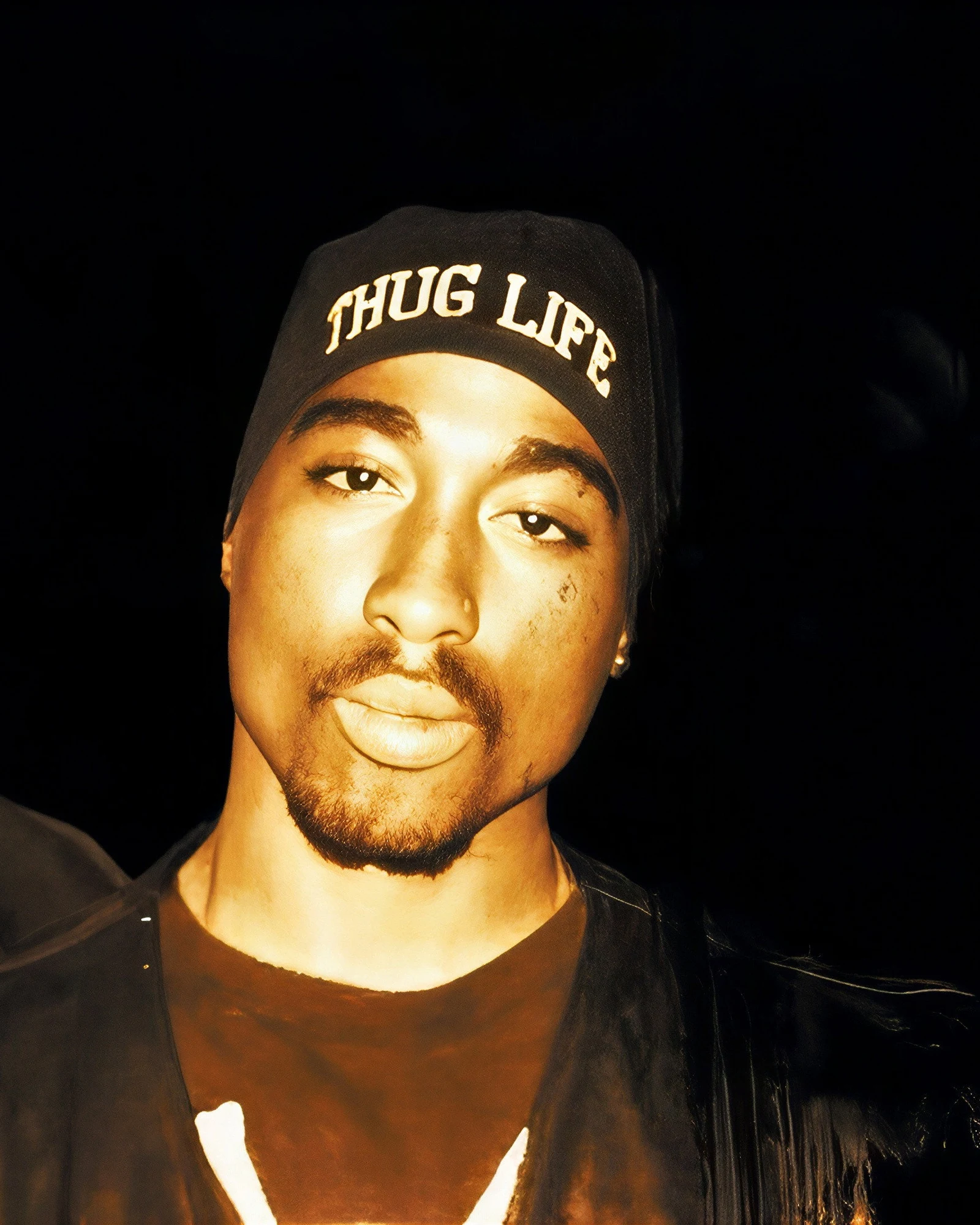 Tupac Shakur, bonnet noir « Thug Life » et regard droit vers l’objectif, sur une photo d’époque reprise dans le documentaire Biggie & Tupac (2002) de Nick Broomfield.