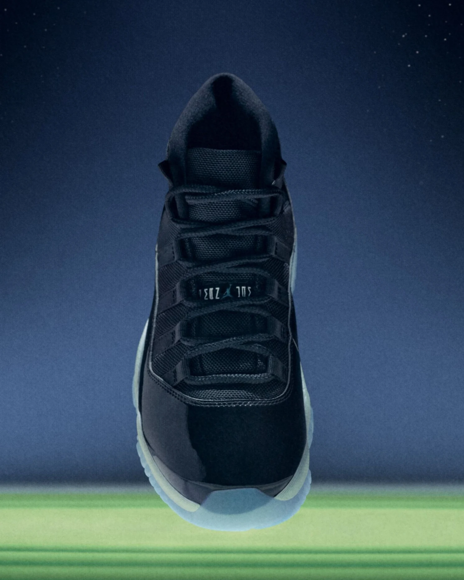 Une Air Jordan 11 Retro OG « Space Jam », noire en cuir verni avec semelle translucide bleutée, vue de face et en entier sur un fond de ciel étoilé.