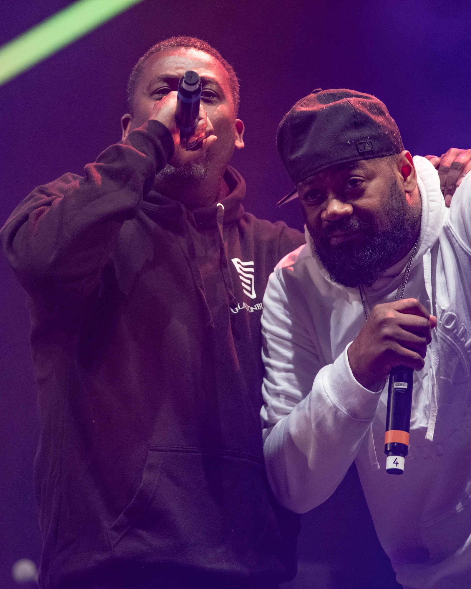 Deux membres du Wu-Tang Clan, l’un en sweat noir, l’autre en sweat blanc et casquette, rappent côte à côte sur la scène West Holts du festival de Glastonbury, le 29 juin 2019.