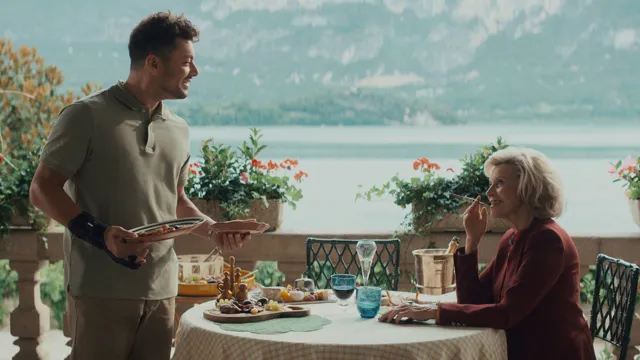 Image officielle de La Maison de nos rêves : un repas en terrasse au bord d’un lac.